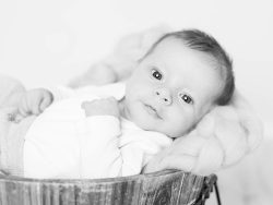 nyfödd baby vilar i en träbalja på en flätad naturfärgad filt i dämpad belysning