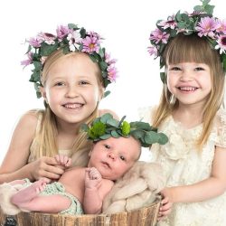 tre syskon med blomsterkransar på huvudet skrattar tillsammans
