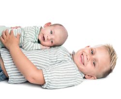 en glad liten nyfödd pojke ligger på sin brors mage, båda skrattar och är glada